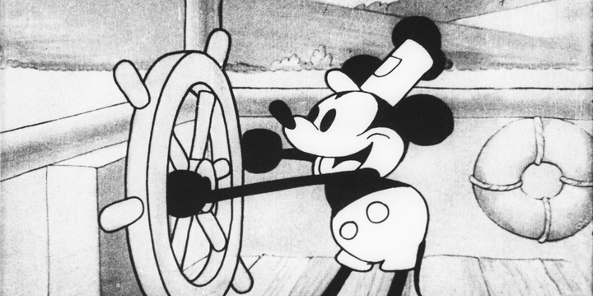 Mickey Mouse en noir et blanc est entrain de tourner la roue d'un bateau avec un sourire au visage. Il a un chapeau sur la tête. Il y a des petites montages en arrière de lui.